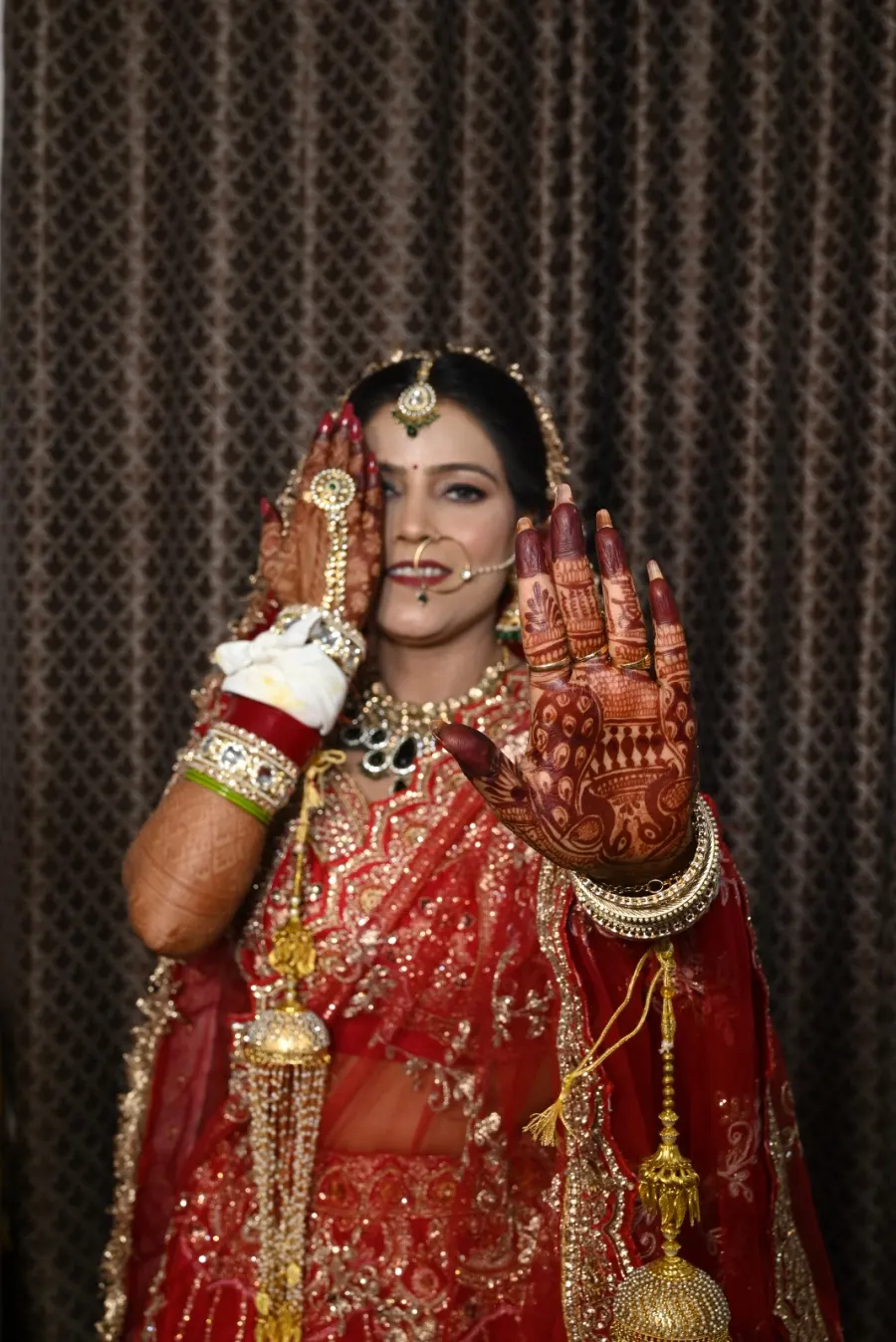 Bride raising her mehendi-covered hand for a bridal portrait