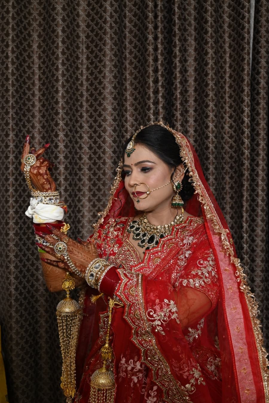 Bride adjusting her bangles in a red bridal lehenga
