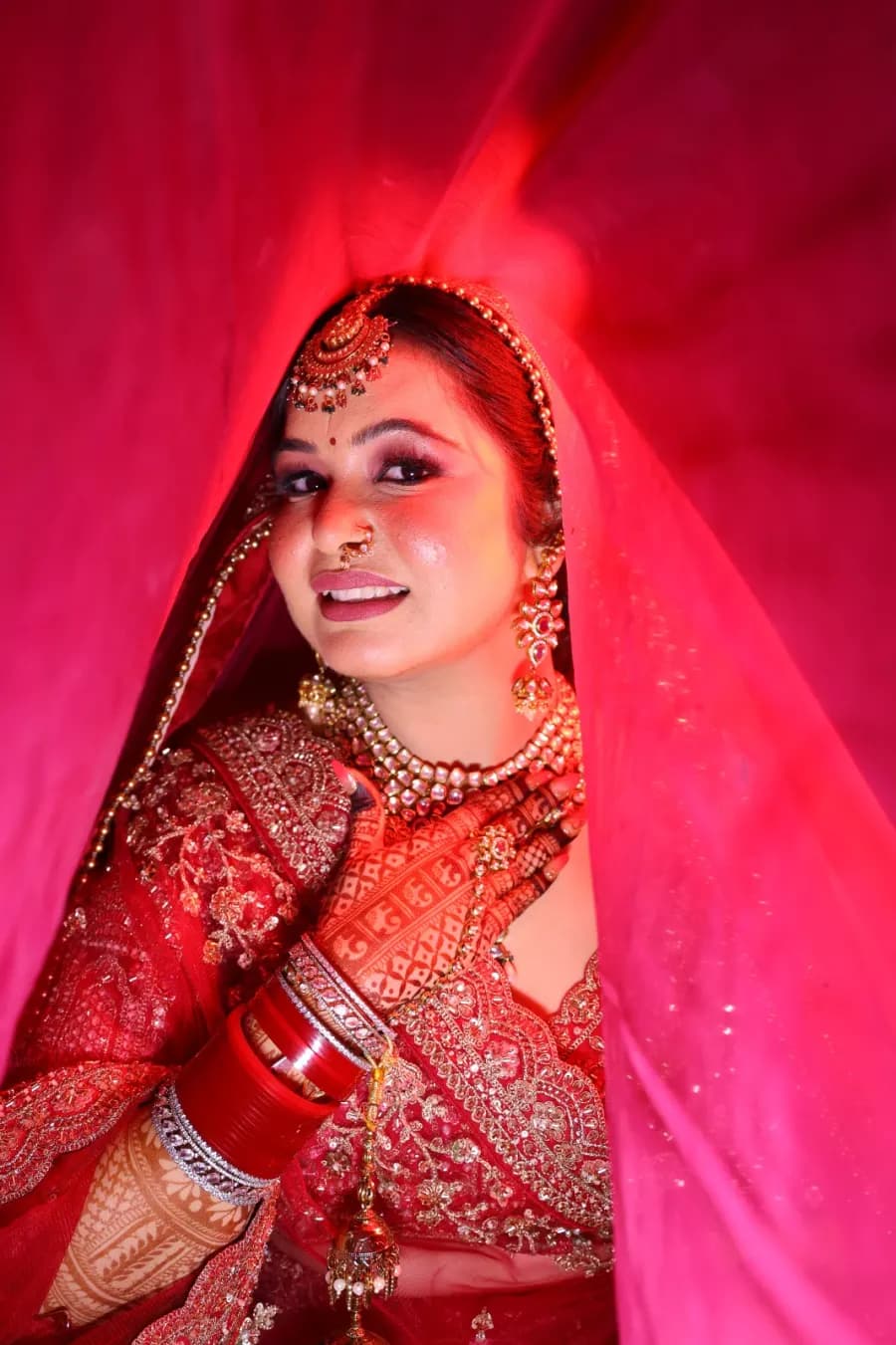 Bride framed by a flowing red dupatta under dramatic lighting