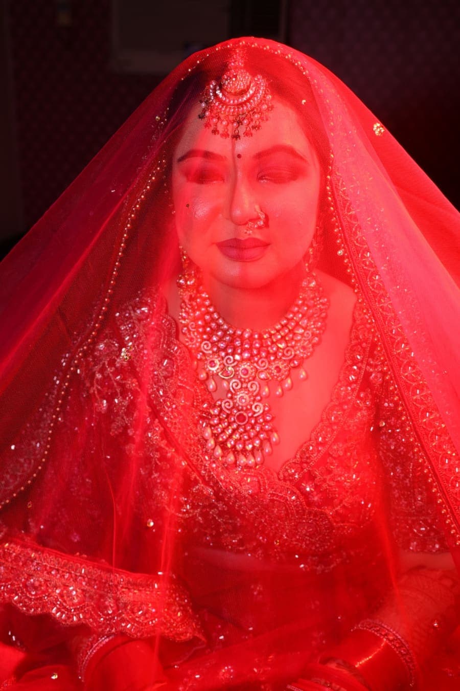 Bride glowing under a red-lit veil