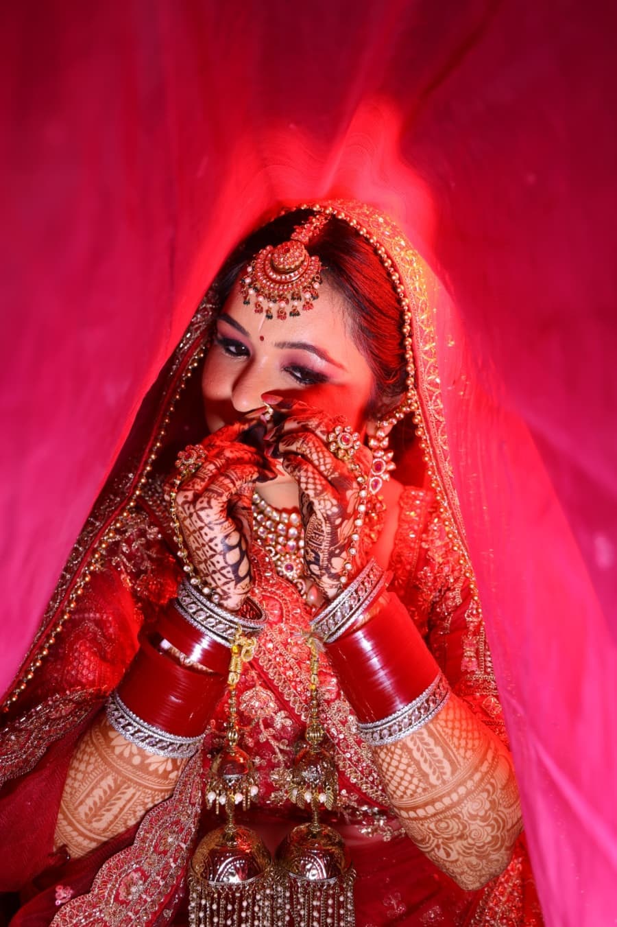 Bride covering her face demurely under the red veil
