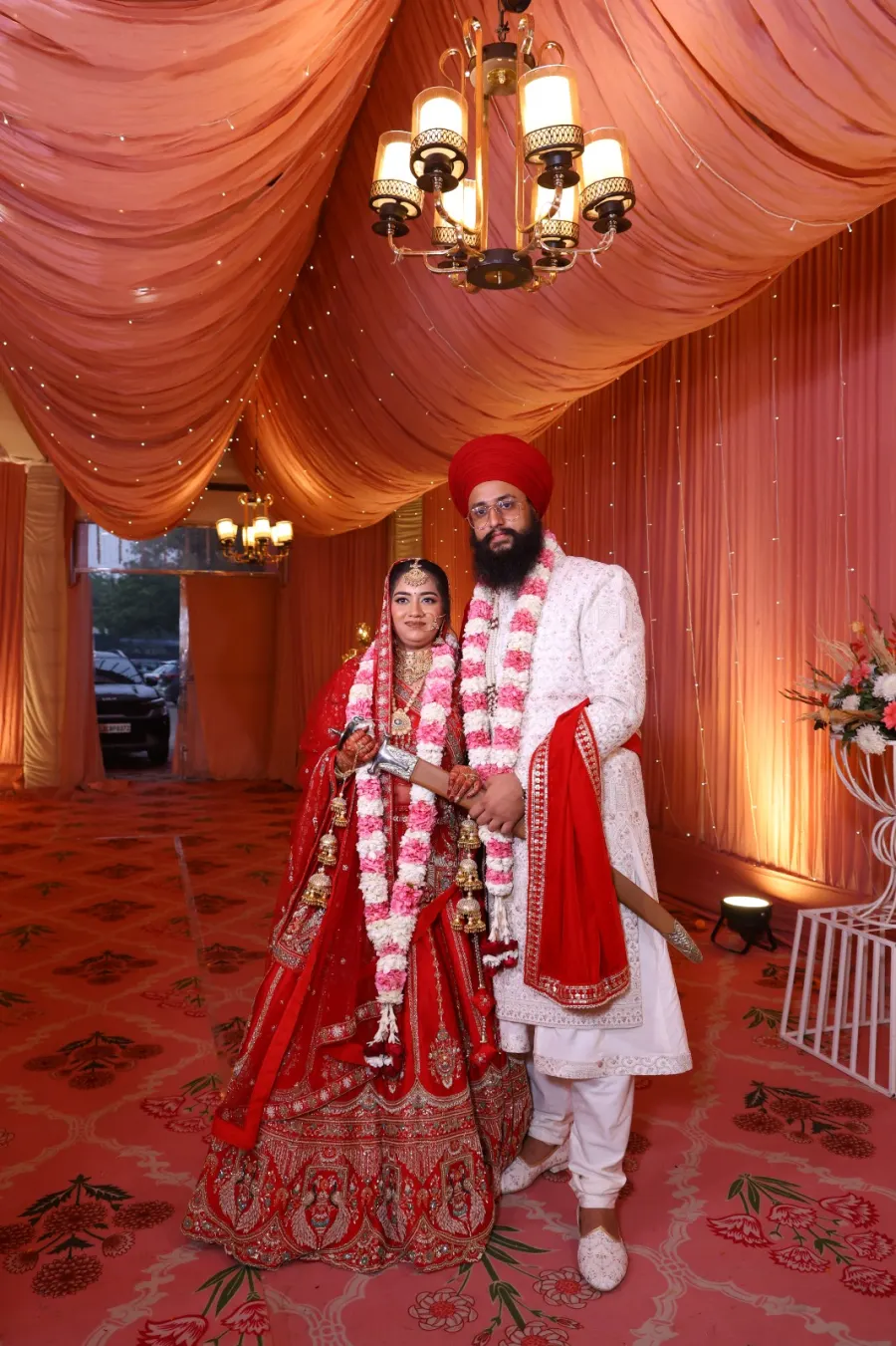 Newlywed couple walking hand in hand beneath the mandap drapes