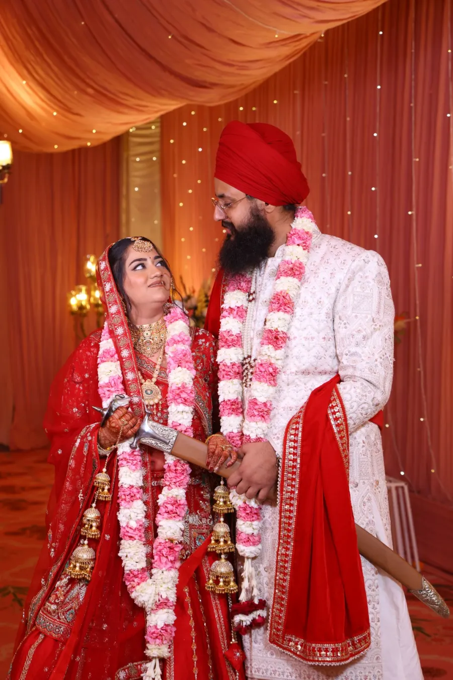 Couple sharing a smile, floral jaimala garlands around their necks