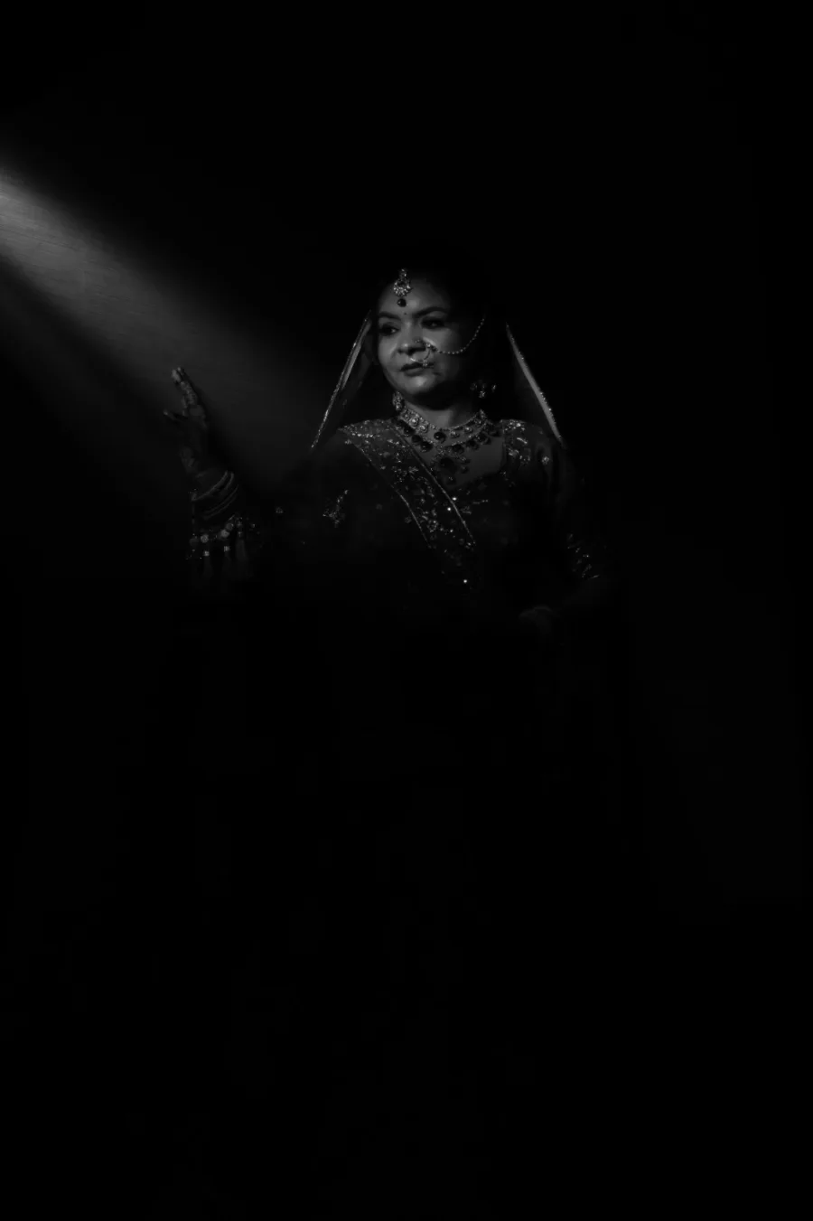 Moody spotlight portrait of the bride against a dark backdrop