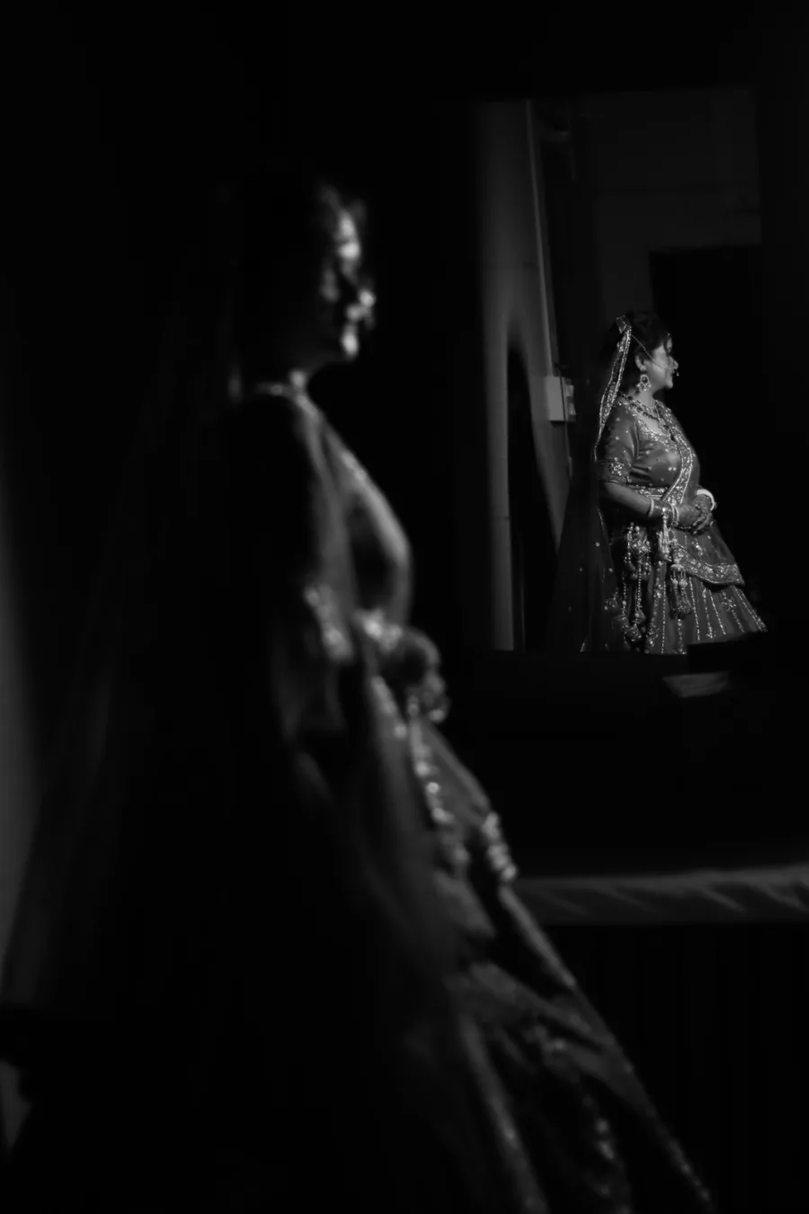 Layered portrait — a bride in soft focus in front, another glowing in the light behind