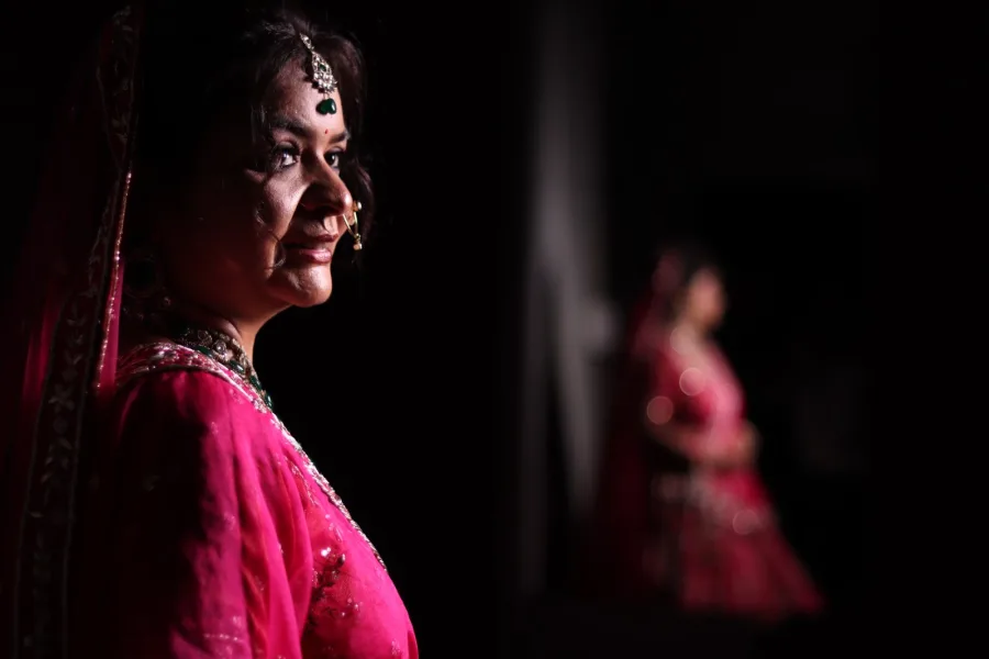 Close portrait of a bride in a pink lehenga, a second bride blurred behind her