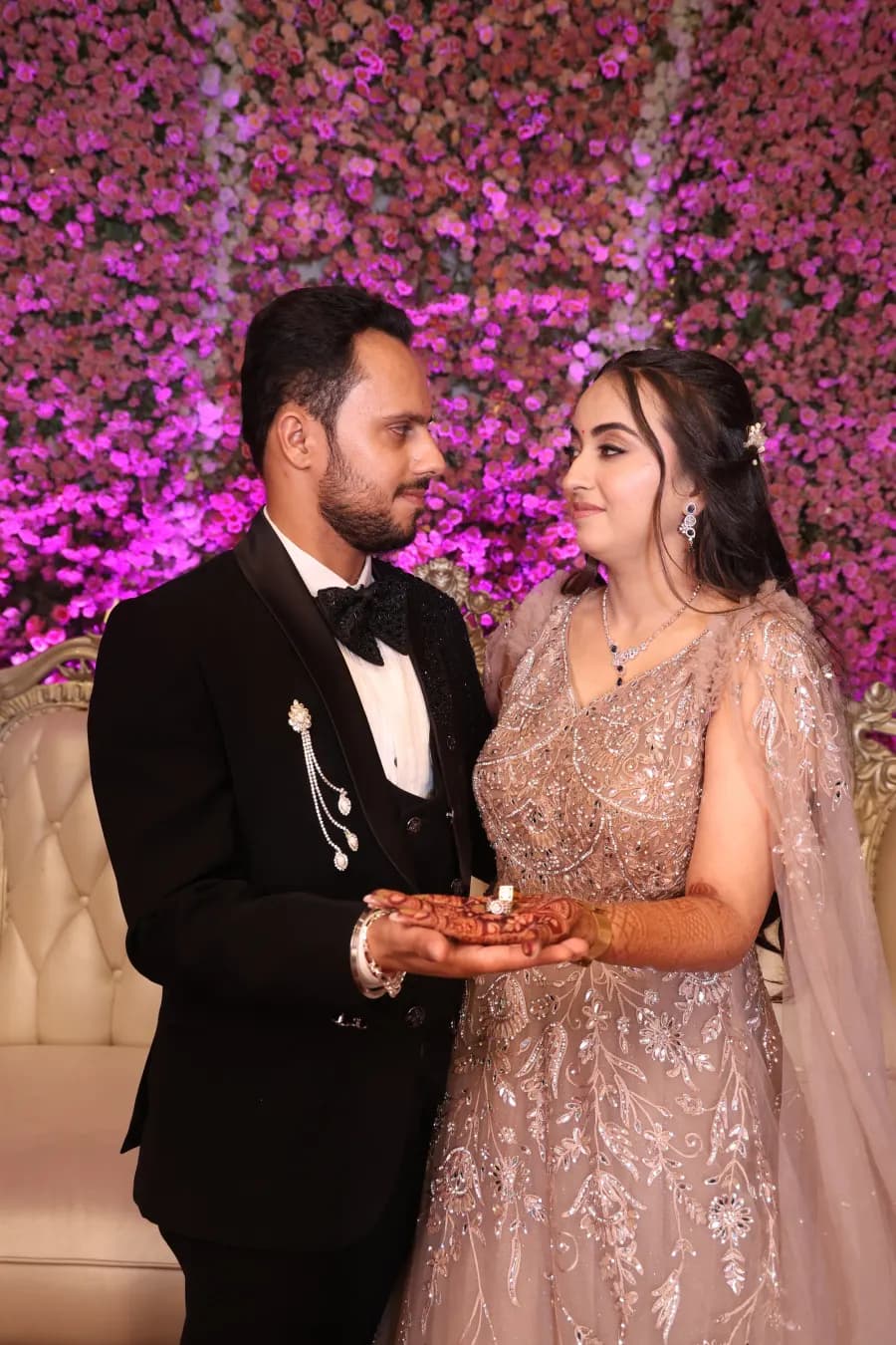 Couple sharing a smile in front of a floral backdrop